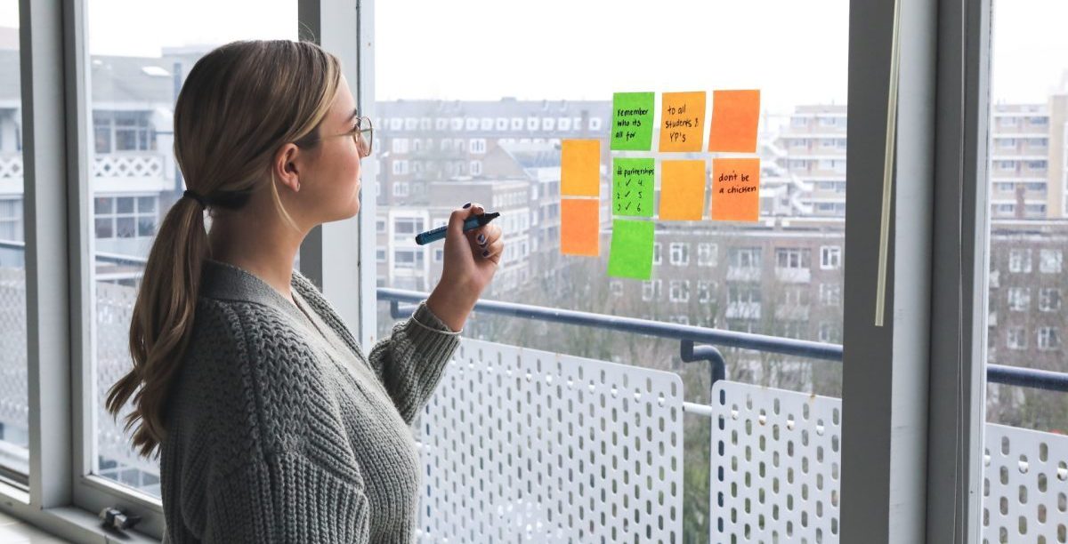Kvinne som skriver på Post-it lapper på vinduet